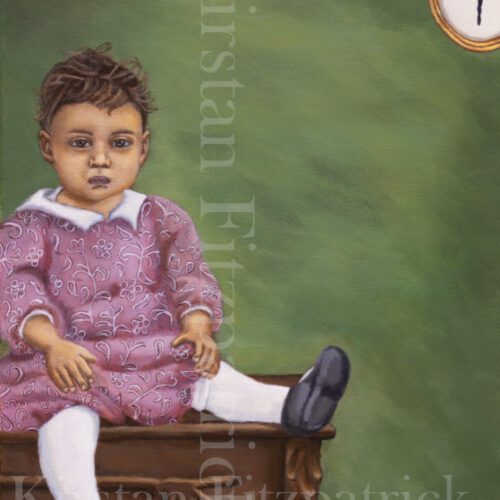 African American Toddler posing for picture, sitting on a table with a picture of a ballerina in upper right hand corner of image.