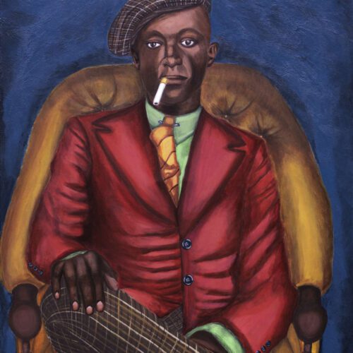 African American gentleman wearing red jacket with green shirt and orange tie, plaid cap and pants, sitting in an orange club chair.