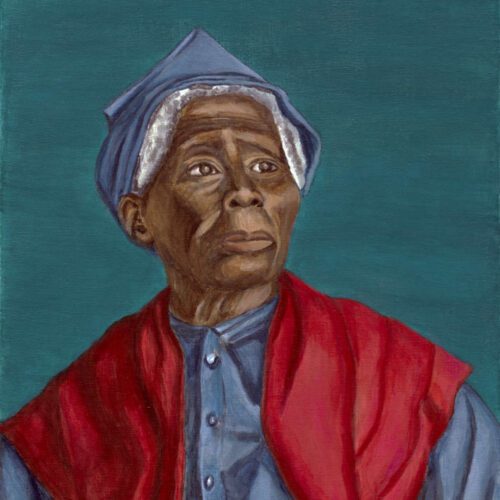 Older woman sitting in front of blue background wearing blue dress and blue handkerchief on her head with red shawl