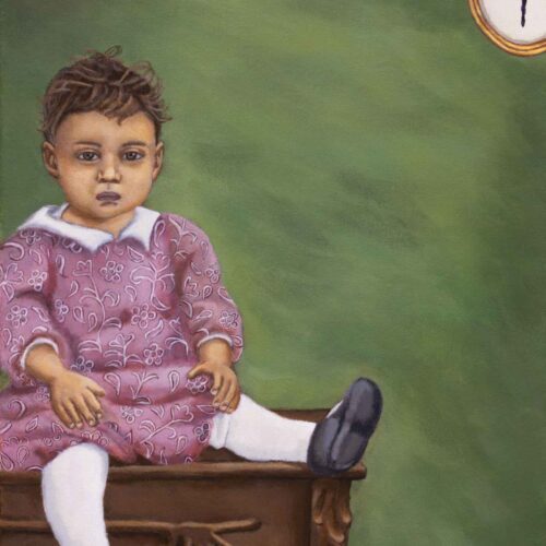 African American Toddler posing for picture, sitting on a table with a picture of a ballerina in upper right hand corner of image.